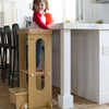 A child stands at a kitchen counter in the Explore 'N Store Learning Tower.  He is holding a red ball.