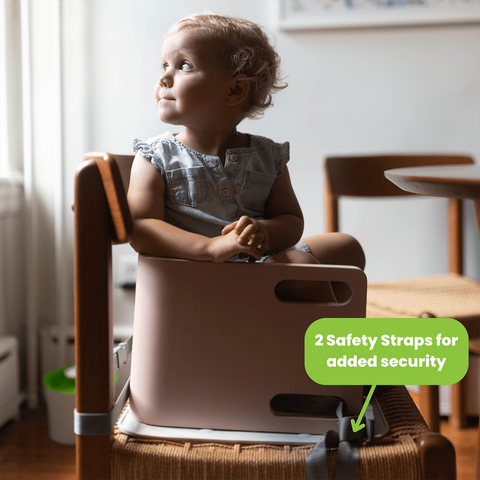 A young girl is sitting in the 3-in-1 Learning Booster and Step Stool.