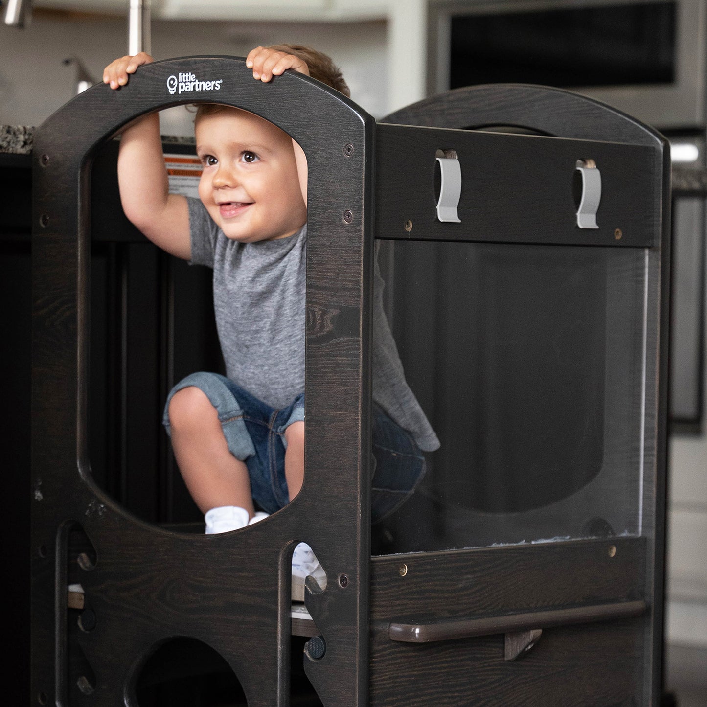 A young boy is standing in the Chef Series Learning Tower.