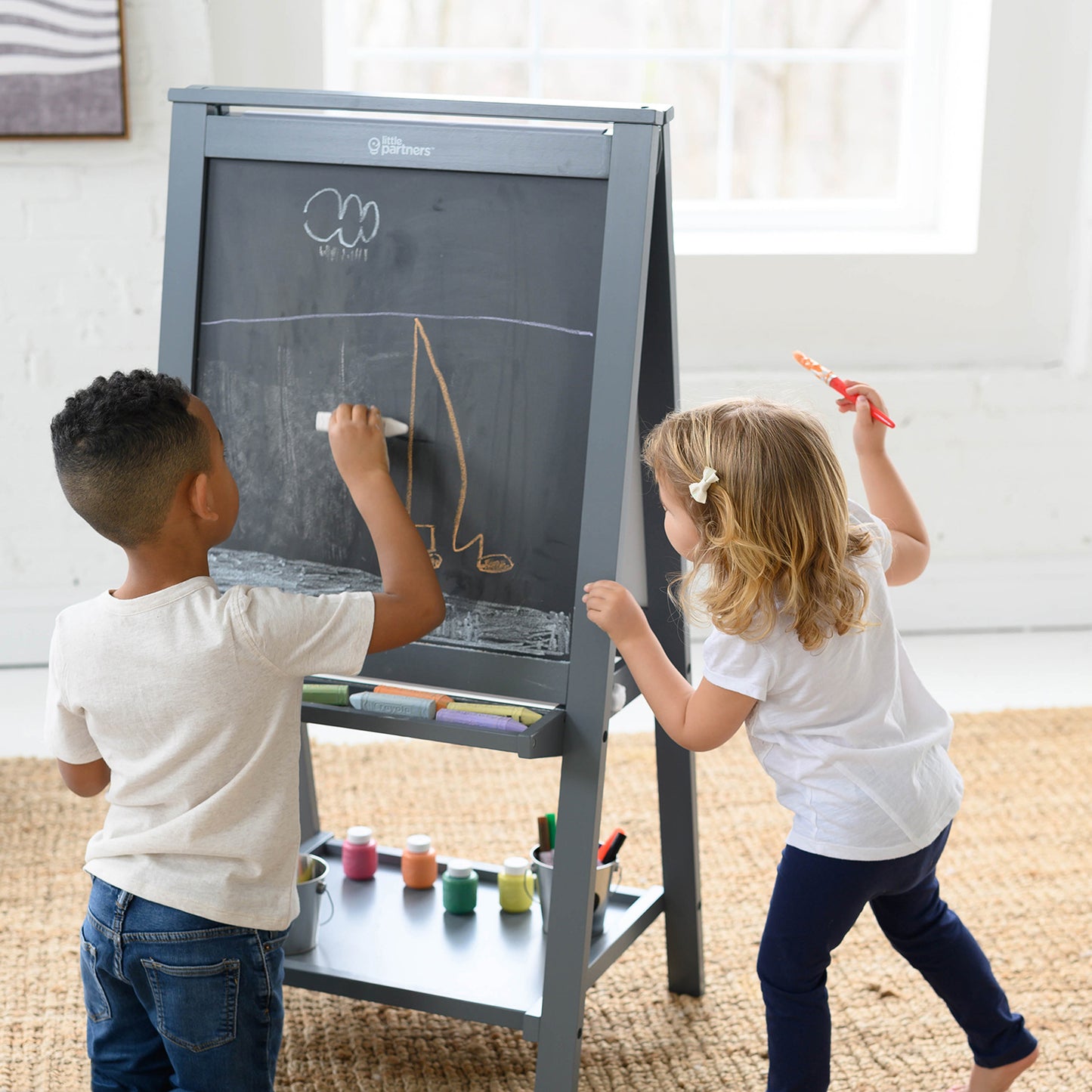 A young girl and boy are drawing on the Artist EZ Easel.