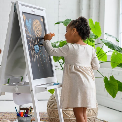 A young girl is drawing on the Artist EZ Easel with chalk.