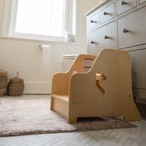 The StepUp Step Stool sits on the ground by the bathroom sink.