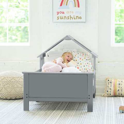 A young girl is laying in the Lil House Toddler Bed.