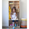 A young girl is sitting on the bench of the Learn N Store Cubby.  She is reading a book.