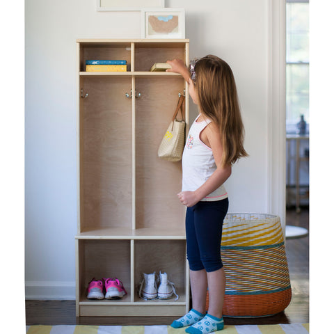 A young girl places a book on the top shelf of the Learn N Store Cubby.