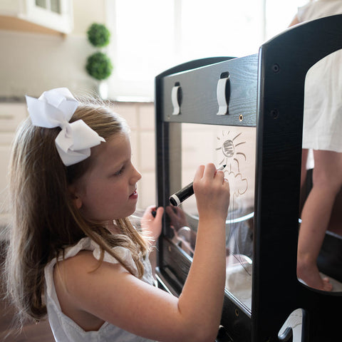 A young girl is drawing on the included plexiglass panel.