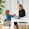 A young girl sits at the table in the 3-in-1 Learning Booster and Step Stool.