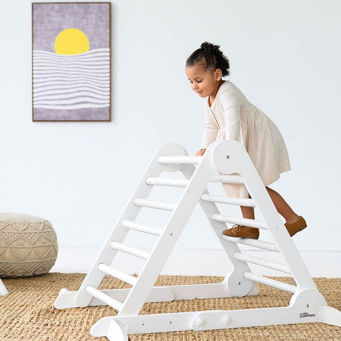 A young girl is climbing on the Learn N Climb Triangle in Soft White.