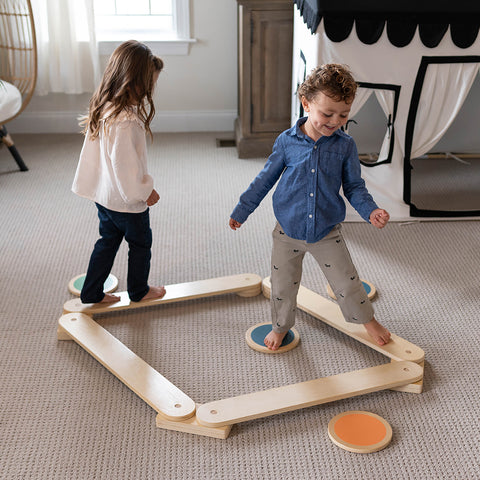 A young girl and boy are walking on the balance beam of the Learn 'N Balance Set.