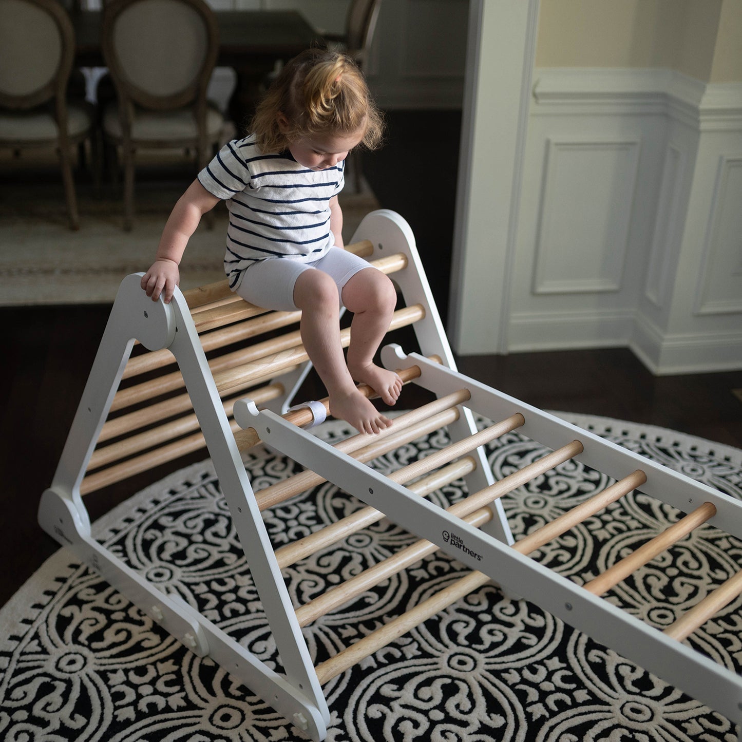 A young girl is climbing on the Climbing Ladder, which is connected to the Climbing Triangle.